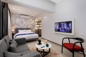 A modern hotel room with a bed, a sofa, a TV, and a small table. - Lovely Home at 22 by Spacey #49 (cairo)