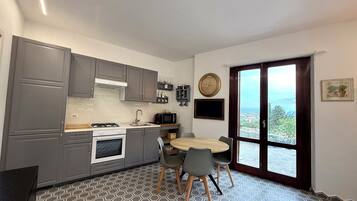 Una cucina compatta con mobili grigi, un fornello e un'area pranzo con un tavolo rotondo e sedie.