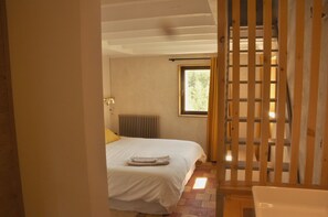 Ein Schlafzimmer mit Bett, Heizkörper, Fenster und einer Holzwand.