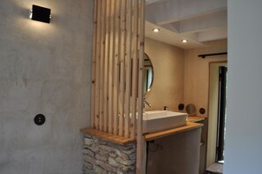 Ein Badezimmer mit Steinwand, Holzvertäfelung, Waschbecken und Spiegel.