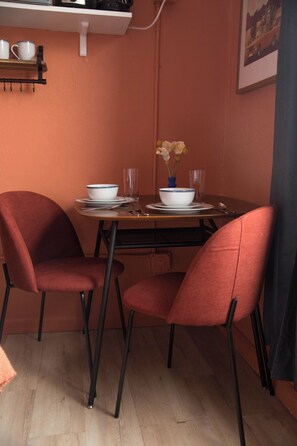 A dining area with a table set for two, featuring a white bowl and a vase with flowers, against a wall with a framed picture. - Peaceful studio with AC in welcoming Los Angeles neighborhood (Los Angeles)
