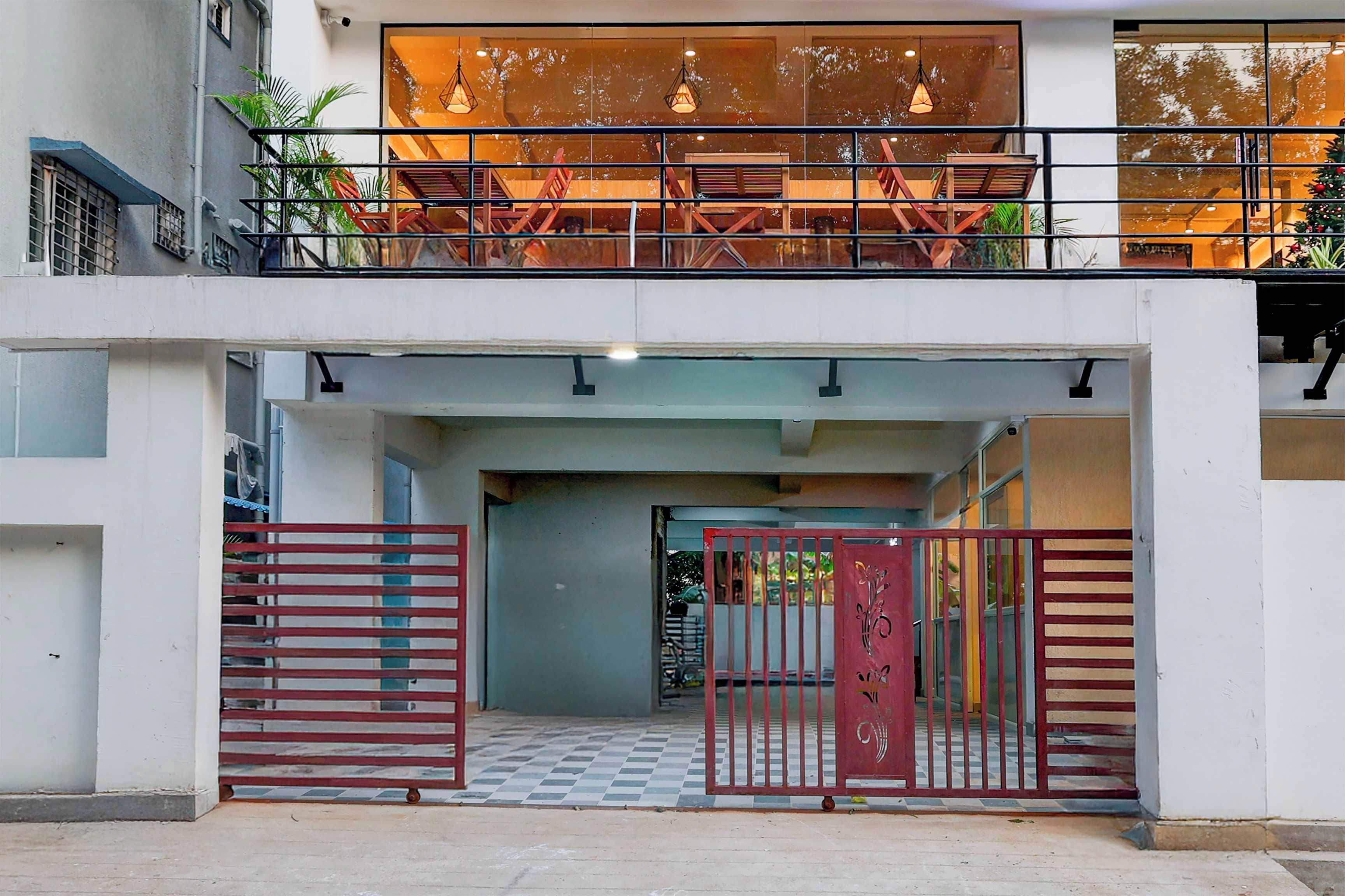 A multi-story building with a gated entrance, a balcony with seating, and a view of the street.