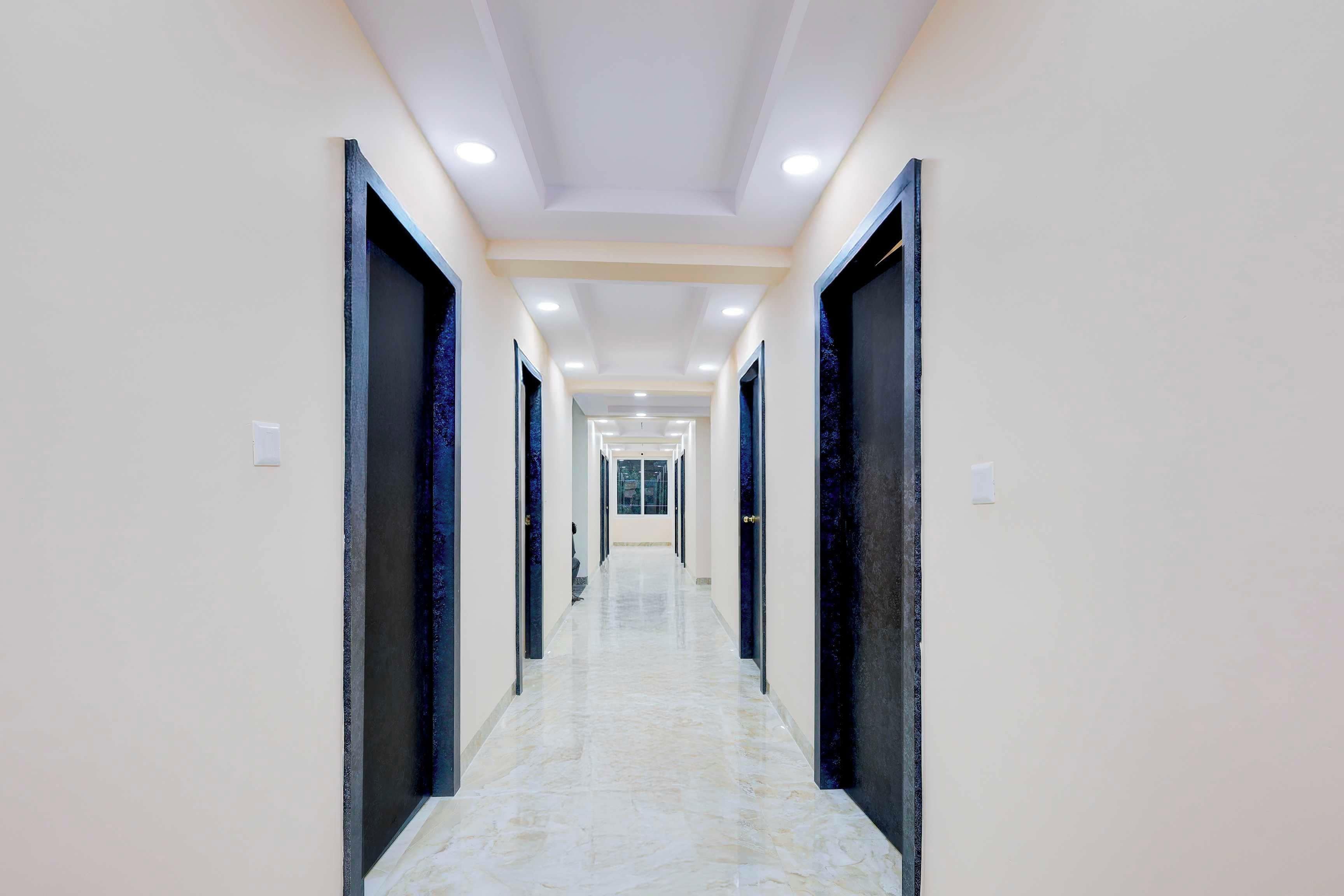 A long, narrow hallway with a marble floor and doors on both sides.
