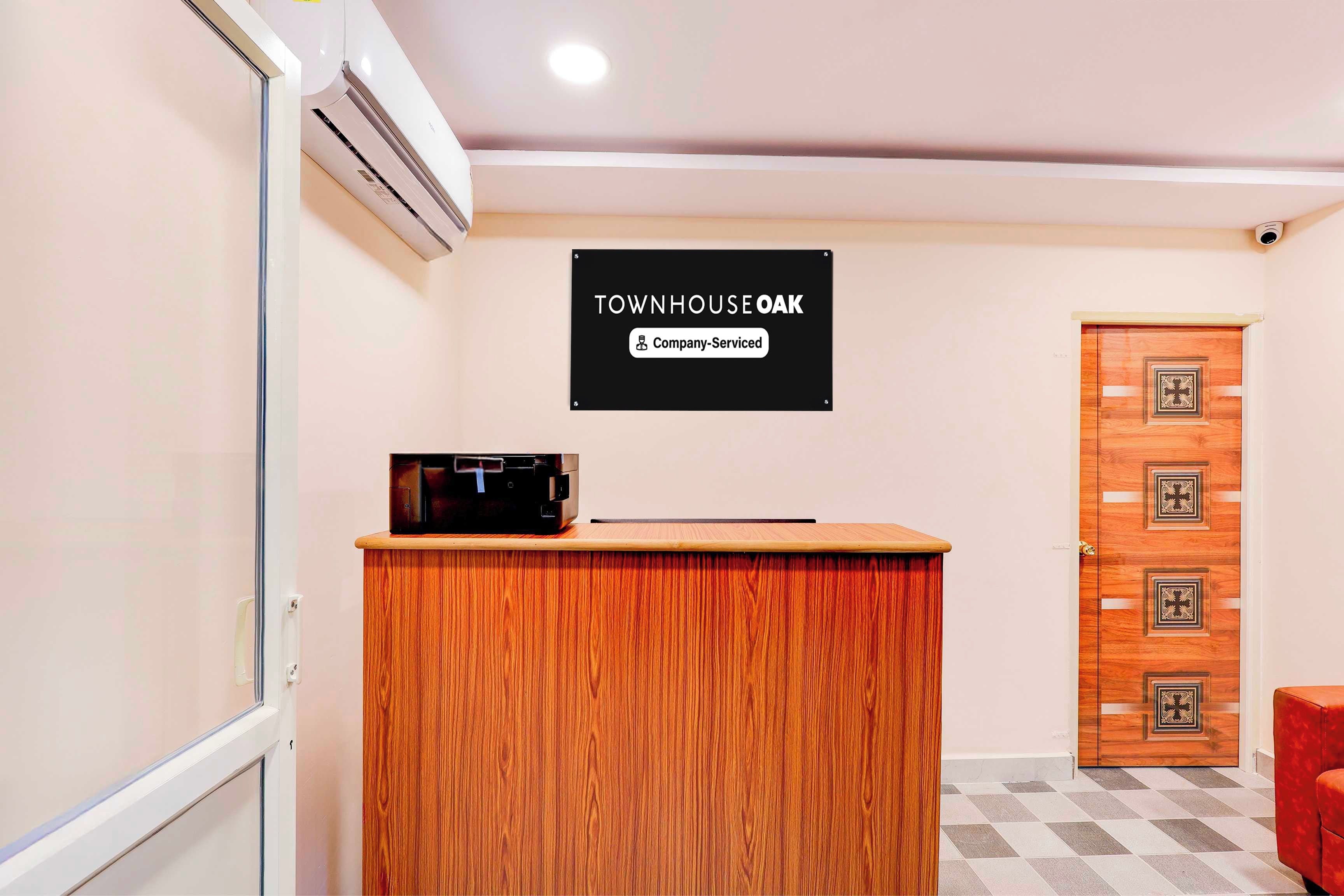 Un comptoir d’accueil avec une enseigne indiquant « TOWNHOUSE OAK » et « Services aux entreprises ».