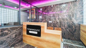 A reception desk labeled 'TOWNHOUSE' with a 'Company-Served' sign, marble walls, and a modern interior design.