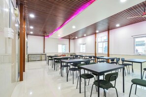 Una habitación amplia con varias mesas y sillas, un techo con detalles de paneles de madera, y un ambiente luminoso y bien iluminado.