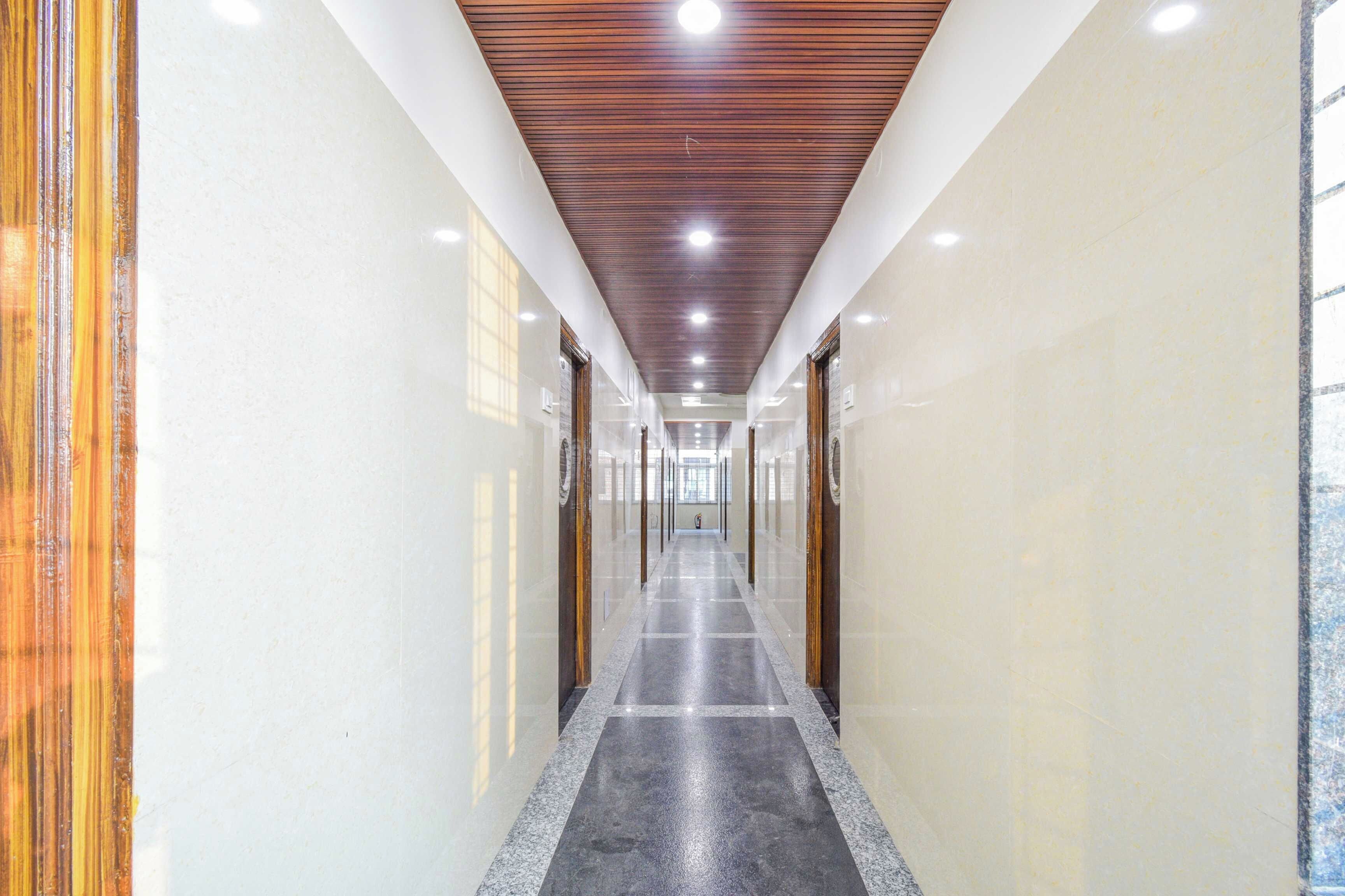 A long, narrow hallway with a polished floor, wooden ceiling panels, and glass doors on both sides.