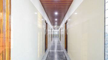 A long, narrow hallway with a polished floor, wooden ceiling panels, and glass doors on both sides.