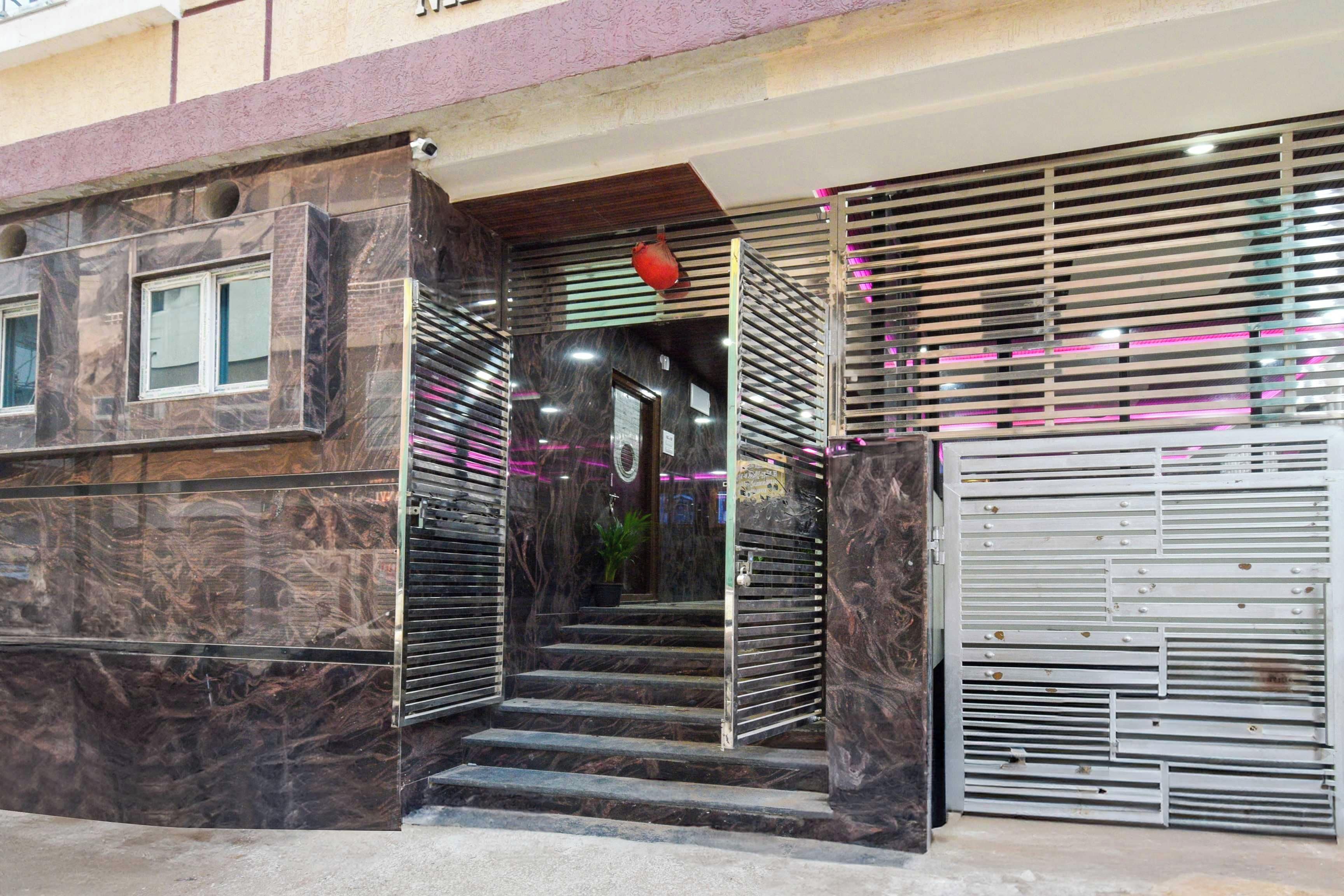 Entrada de um edifício com um conjunto de degraus que levam a uma porta, um portão de segurança e um vaso de planta.