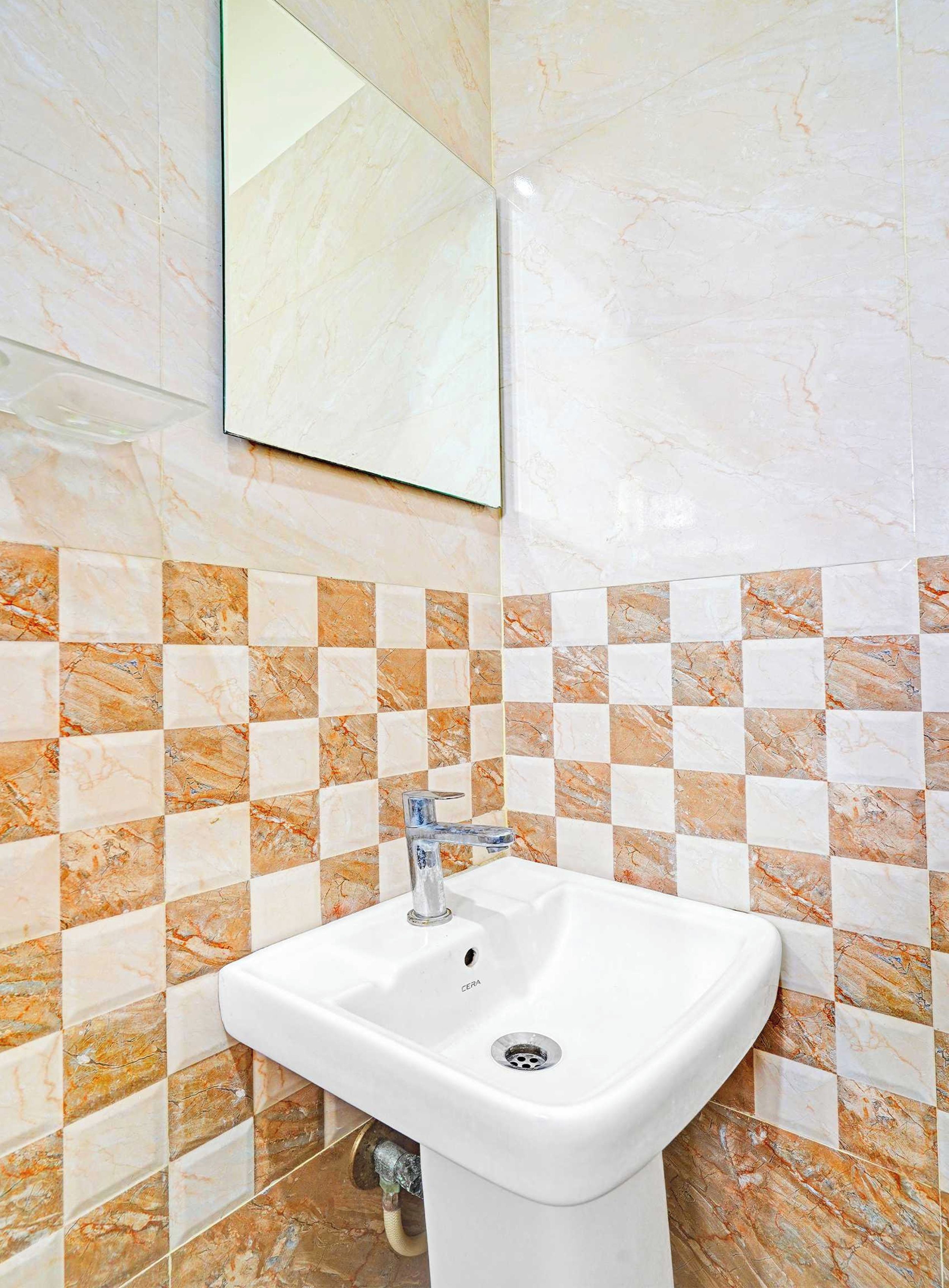 Ein Badezimmer mit einem weißen Waschbecken, einer Fliesenrückwand mit Schachmuster und einem Spiegel darüber.