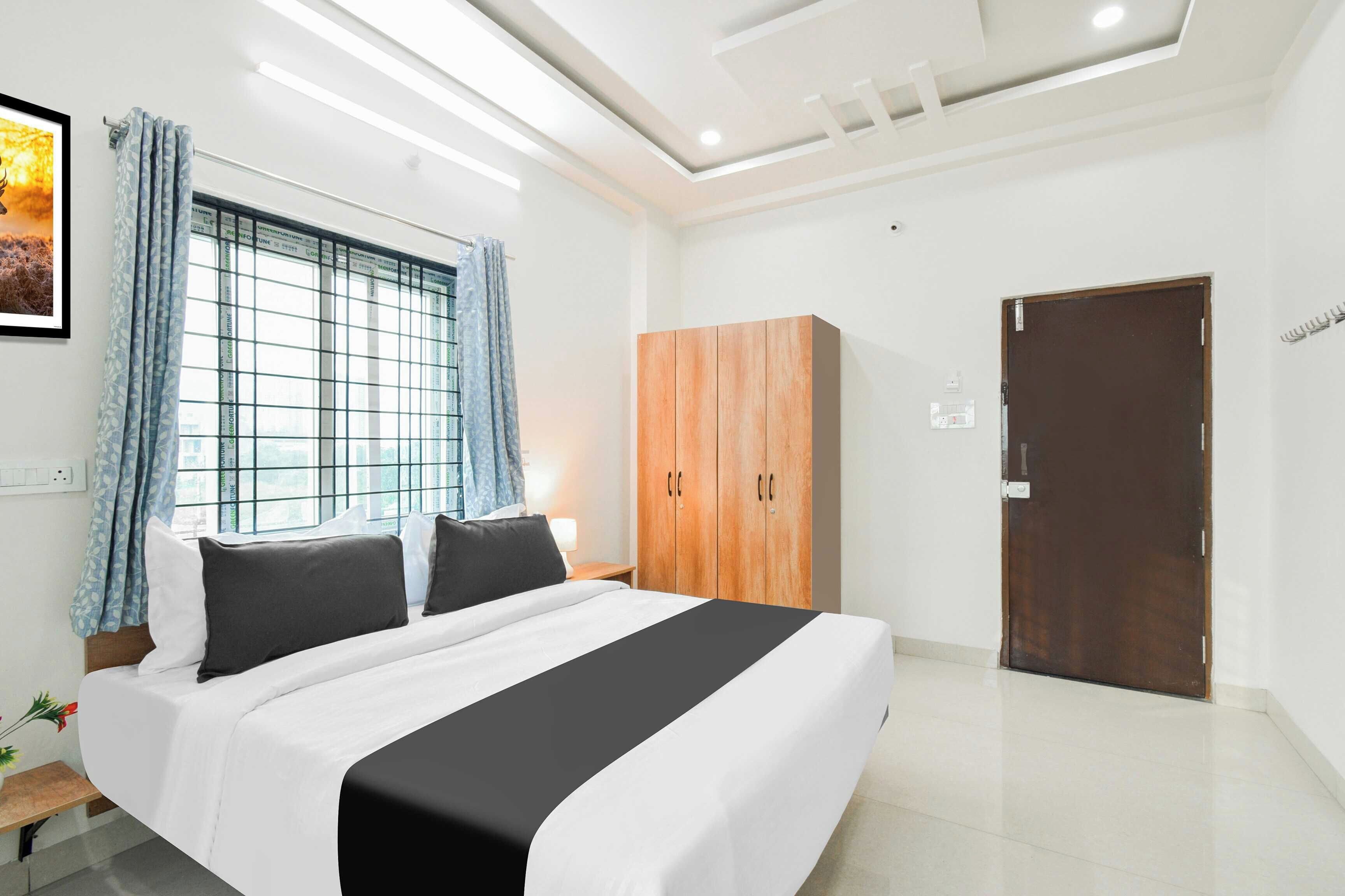 A modern hotel room with a large bed, a wardrobe, and a door.