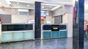 Zona de recepción con pantalla digital, cartel que indica servicio de la empresa y mostrador de recepción.