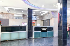 A reception area with a digital display, a sign indicating it's company-serviced, and a reception desk. - Townhouse Kolkata Raghunathpur (Barasat)