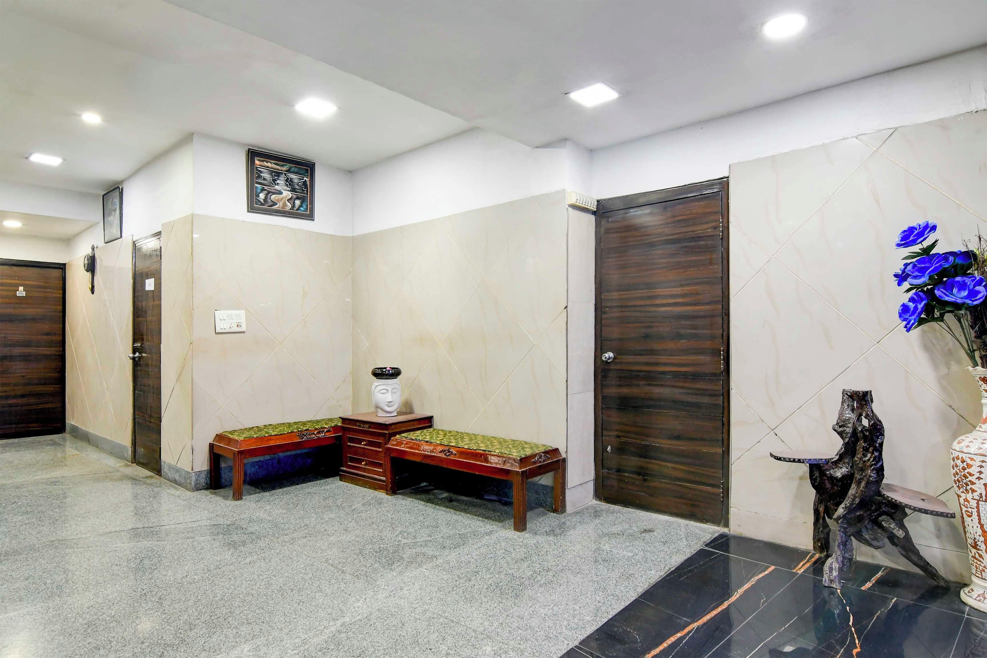 Un vestíbulo de hotel con una mesa de recepción, una obra de arte colgada en la pared y un jarrón decorativo con flores.