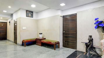 Un vestíbulo de hotel con una mesa de recepción, una obra de arte colgada en la pared y un jarrón decorativo con flores.