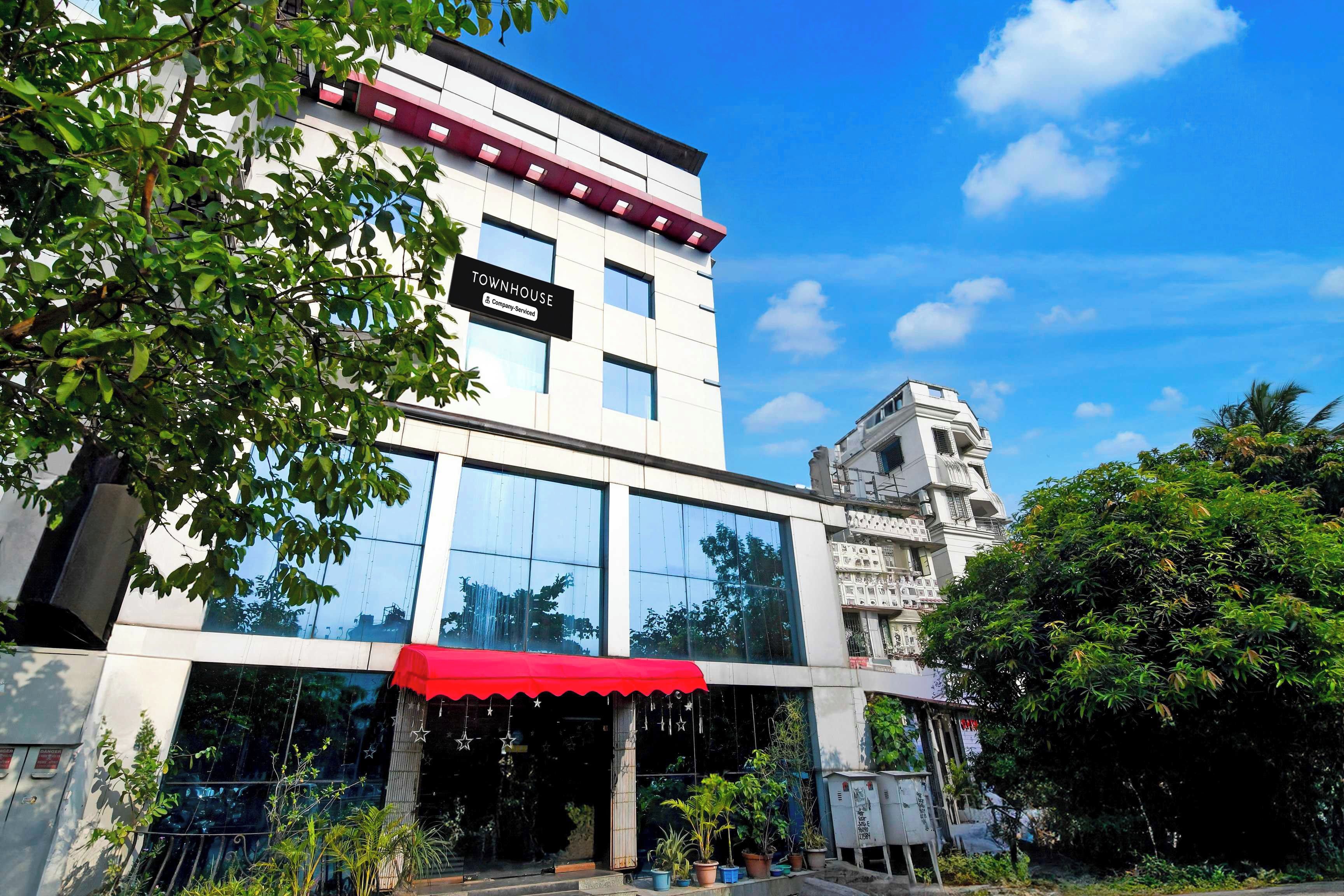 Un edificio moderno con toldo rojo, amplias ventanas y un cartel que indica que es una casa townhouse de servicios empresariales.