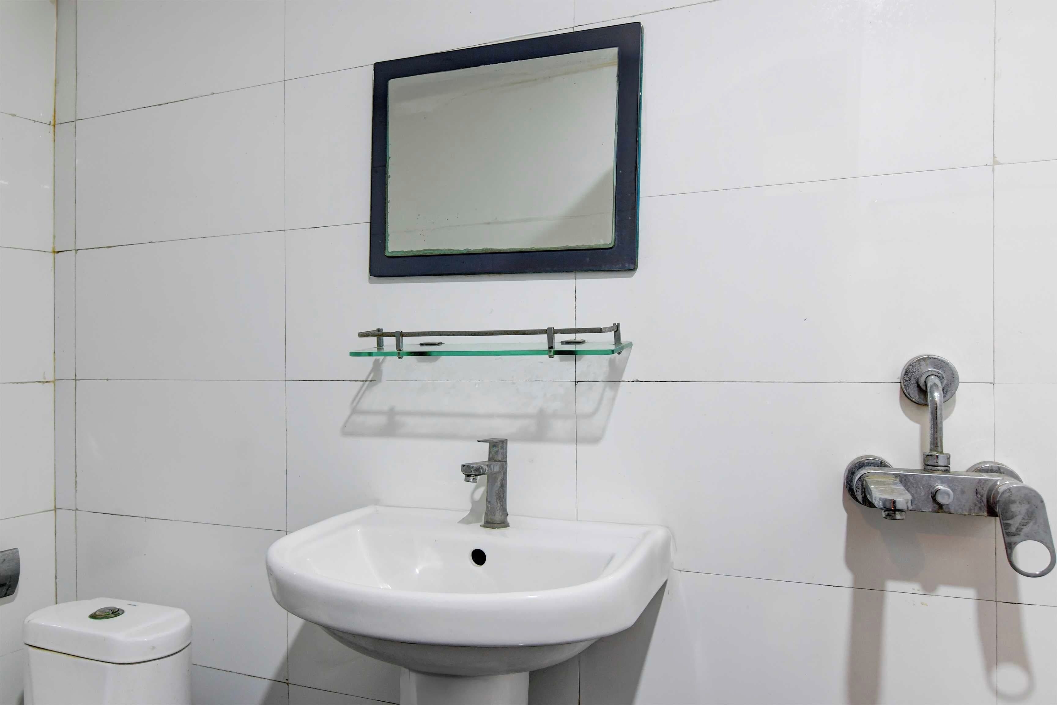 A bathroom with a white sink, a mirror, and a soap dispenser.