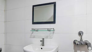 Un baño con lavamanos blanco, espejo y dispensador de jabón.