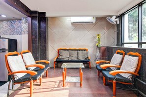 Habitación de hotel con sofá, una mesita y ventanal con vistas.
