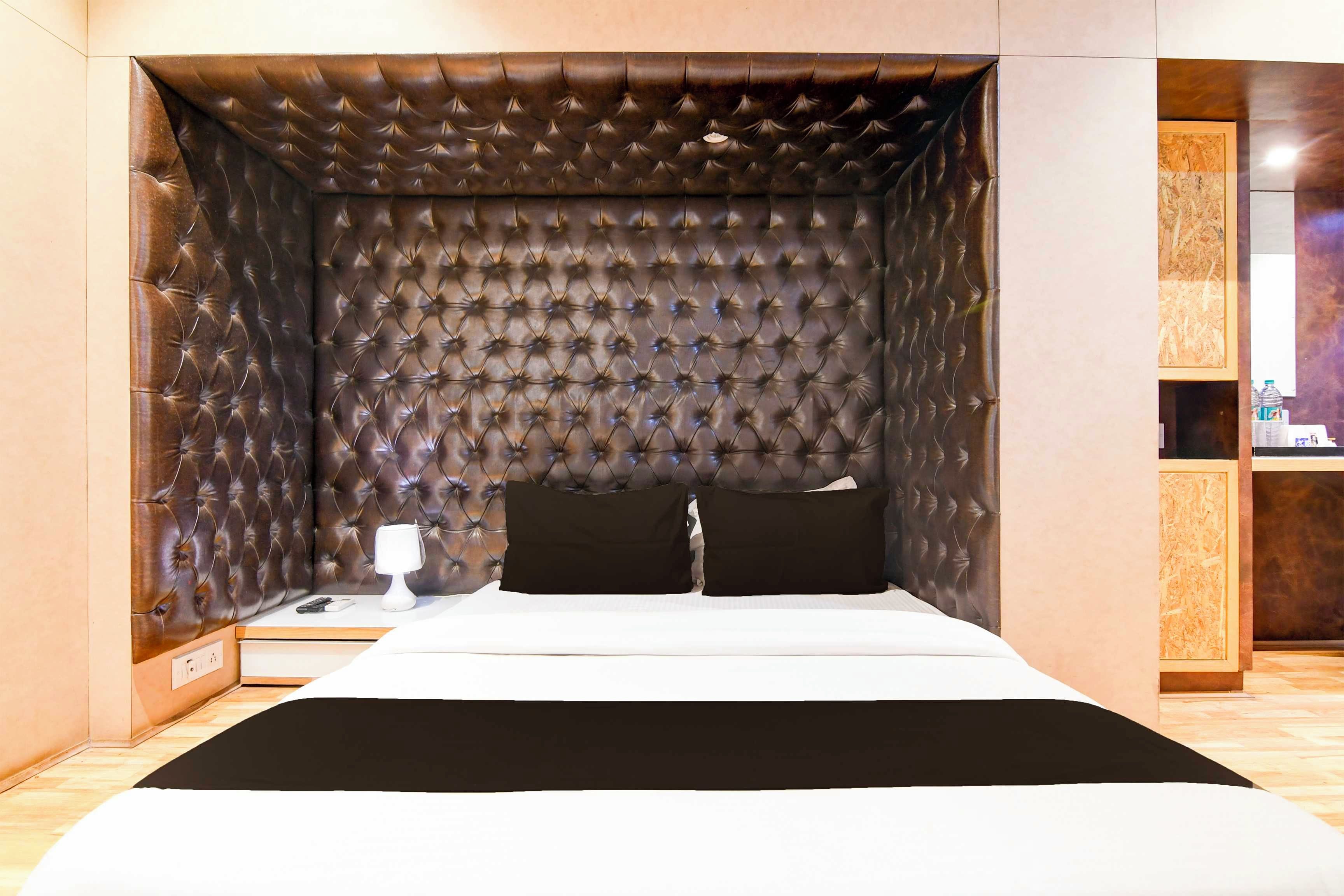 A bedroom with a tufted headboard, a bed with white bedding, a bedside table with a lamp, and a nightstand.