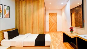Habitación de hotel con cama, escritorio, espejo y un panel de pared de madera.