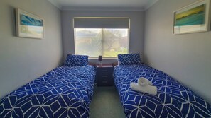 Ein Schlafzimmer mit zwei Betten, einem Fenster und Bildern an den Wänden.