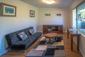 Ein modernes Wohnzimmer mit einem dunkelgrauen Sofa, einem runden Holztisch und einem Kamin mit Büchern.