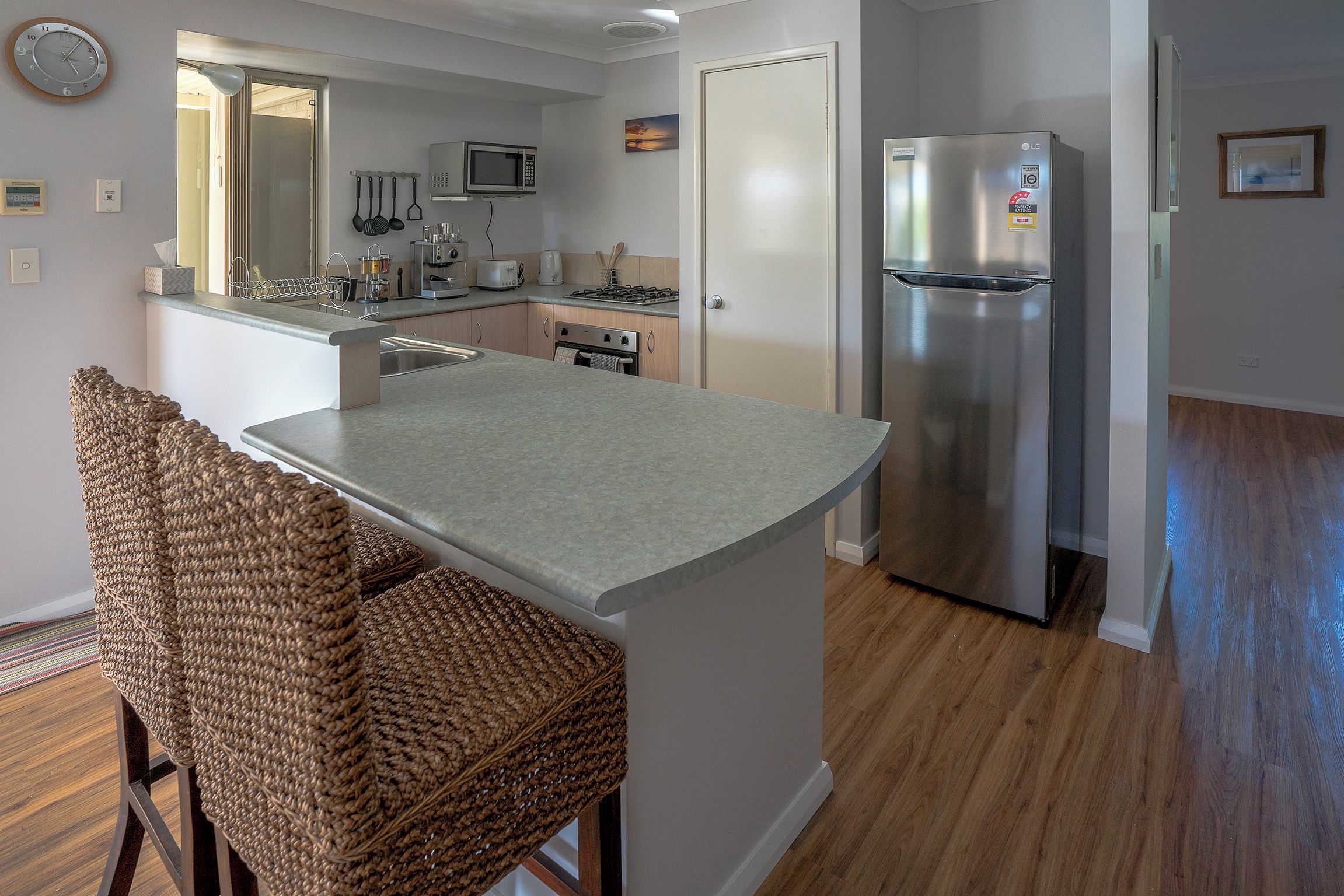 A modern kitchen with a built-in island, stainless steel appliances, and a dining area with wicker chairs.