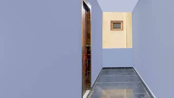 A narrow hallway with a tiled floor and a wooden door on the left.