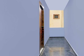 A narrow hallway with a tiled floor and a wooden door on the left. - Townhouse Oak Nizampet X Bus Terminal (Hyderabad)