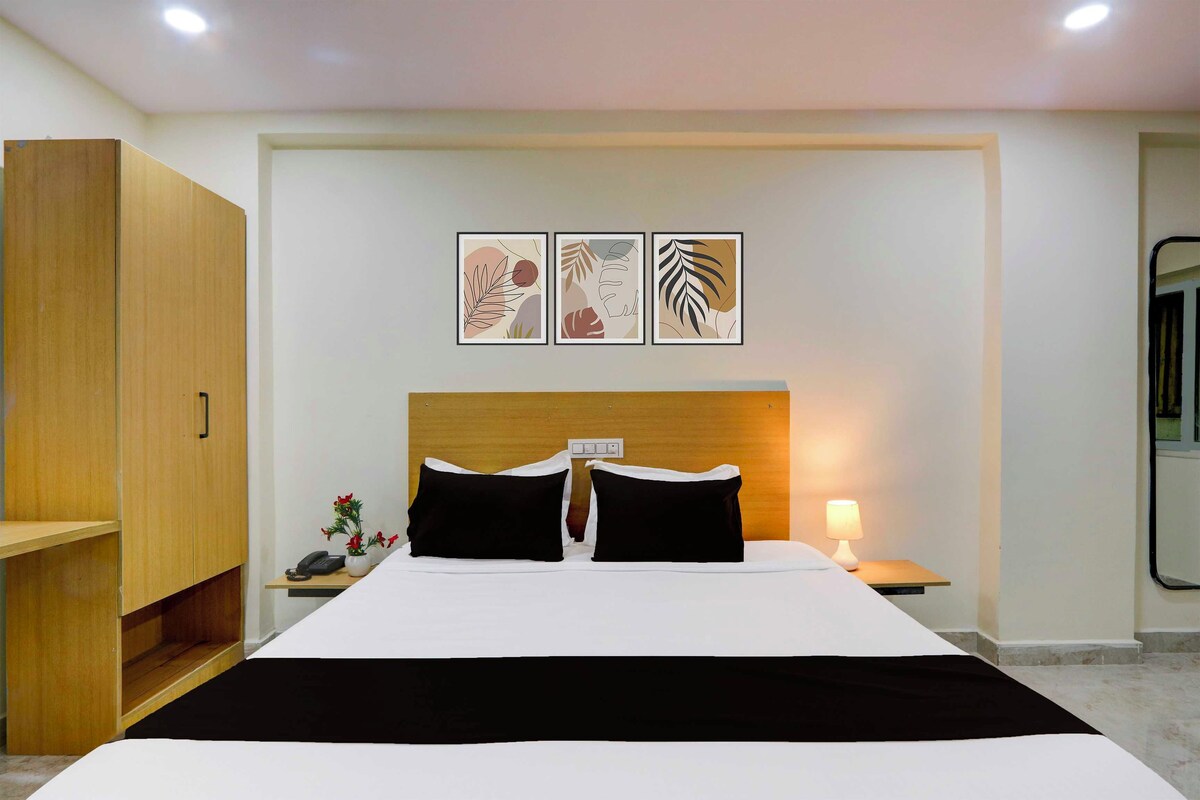 Una habitación de hotel con una cama, mesitas de noche, un armario de madera y tres cuadros enmarcados.