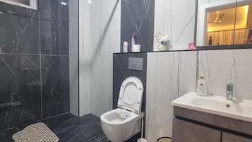 Ein modernes Badezimmer mit Toilette, Waschbecken und Duschbereich.