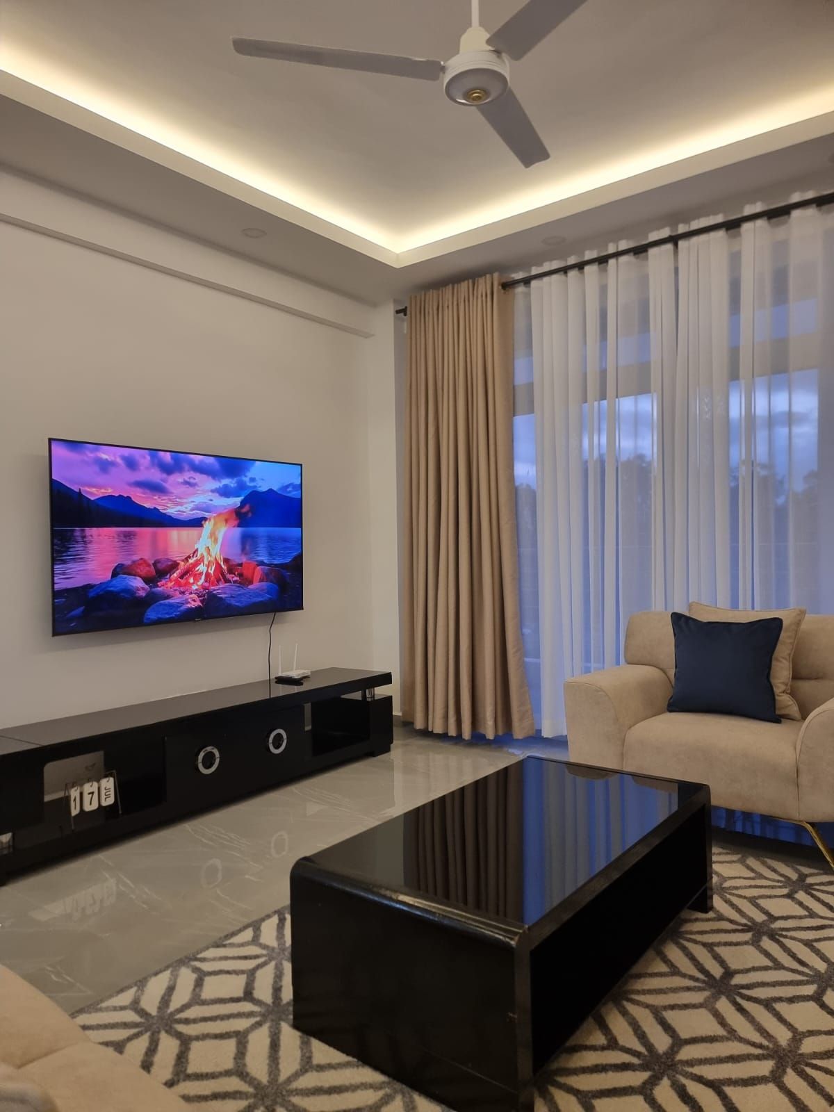 Un salon moderne doté d’un téléviseur à écran plat, d’un ventilateur de plafond, d’un canapé et d’une table basse.