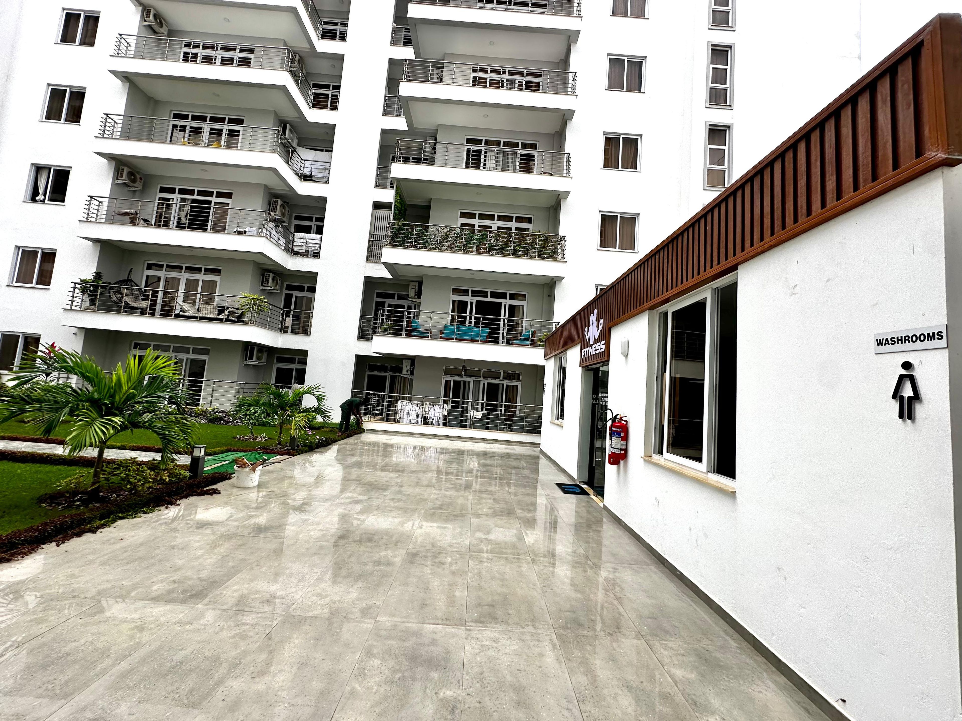 Um edifício residencial com vários andares, varandas, centro de atividades físicas e um aviso indicando a localização dos sanitários.