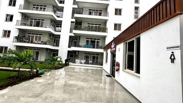 Um edifício residencial com vários andares, varandas, centro de atividades físicas e um aviso indicando a localização dos sanitários.