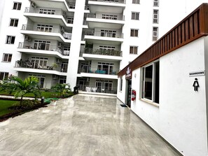 Um edifício residencial com vários andares, varandas, centro de atividades físicas e um aviso indicando a localização dos sanitários.