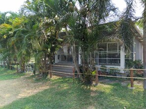 A building with a covered entrance, surrounded by palm trees and a grassy area.