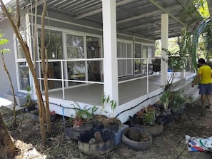A covered outdoor area with a porch, potted plants, and a person in a yellow shirt.