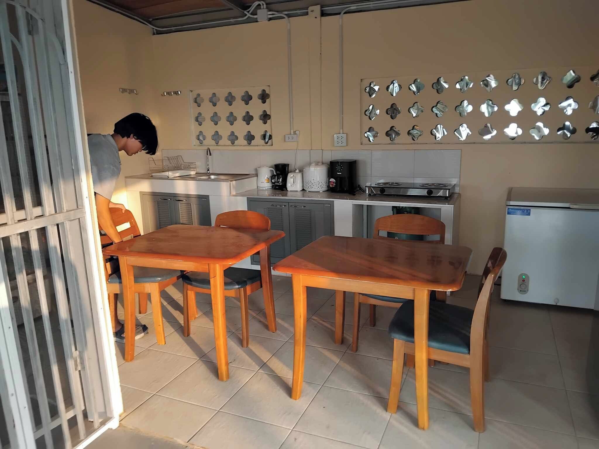Una cocina compacta con comedor, que incluye un refrigerador, estufa, cafetera y una lámpara fijada a la pared.