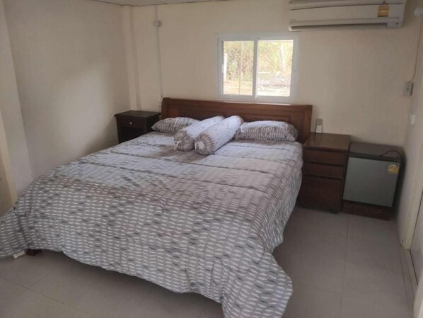 A bedroom with a bed, a nightstand, a dresser, and a window.