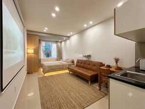 Ein modernes Hotelzimmer mit Bett, Sofa und einer Küchenzeile.