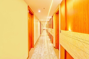 Un couloir d’hôtel avec des portes en bois et un sol à motifs.