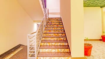 Una escalera con peldaños de diseño geométrico, barandilla de metal y una planta en maceta al final.