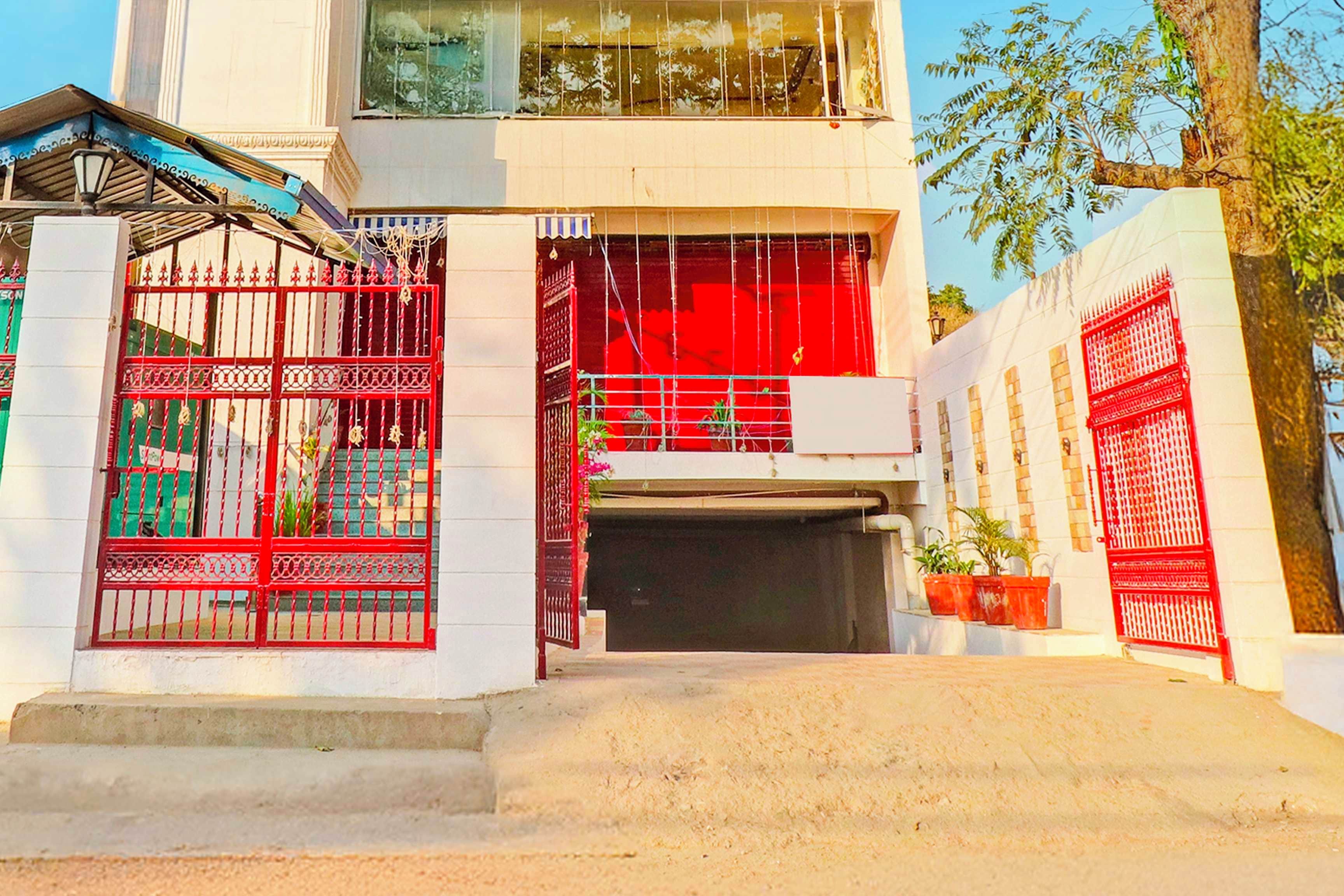 Un edificio con entrada protegida por una reja, puerta de garaje visible y una escalera que lleva a la entrada.