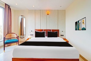 Une chambre d’hôtel avec un grand lit, une chaise, un miroir et des œuvres d’art accrochées au mur.