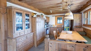 Un interior de madera con una mesa de comedor central, armarios de madera y una pared de piedra.