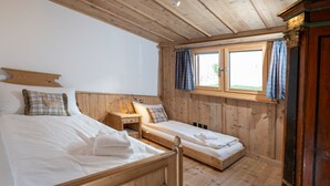 Una habitación de madera con dos camas, una mesita de noche y una ventana con cortinas.