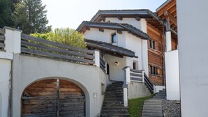 Un edificio con puerta de madera, una escalera y un muro de piedra.