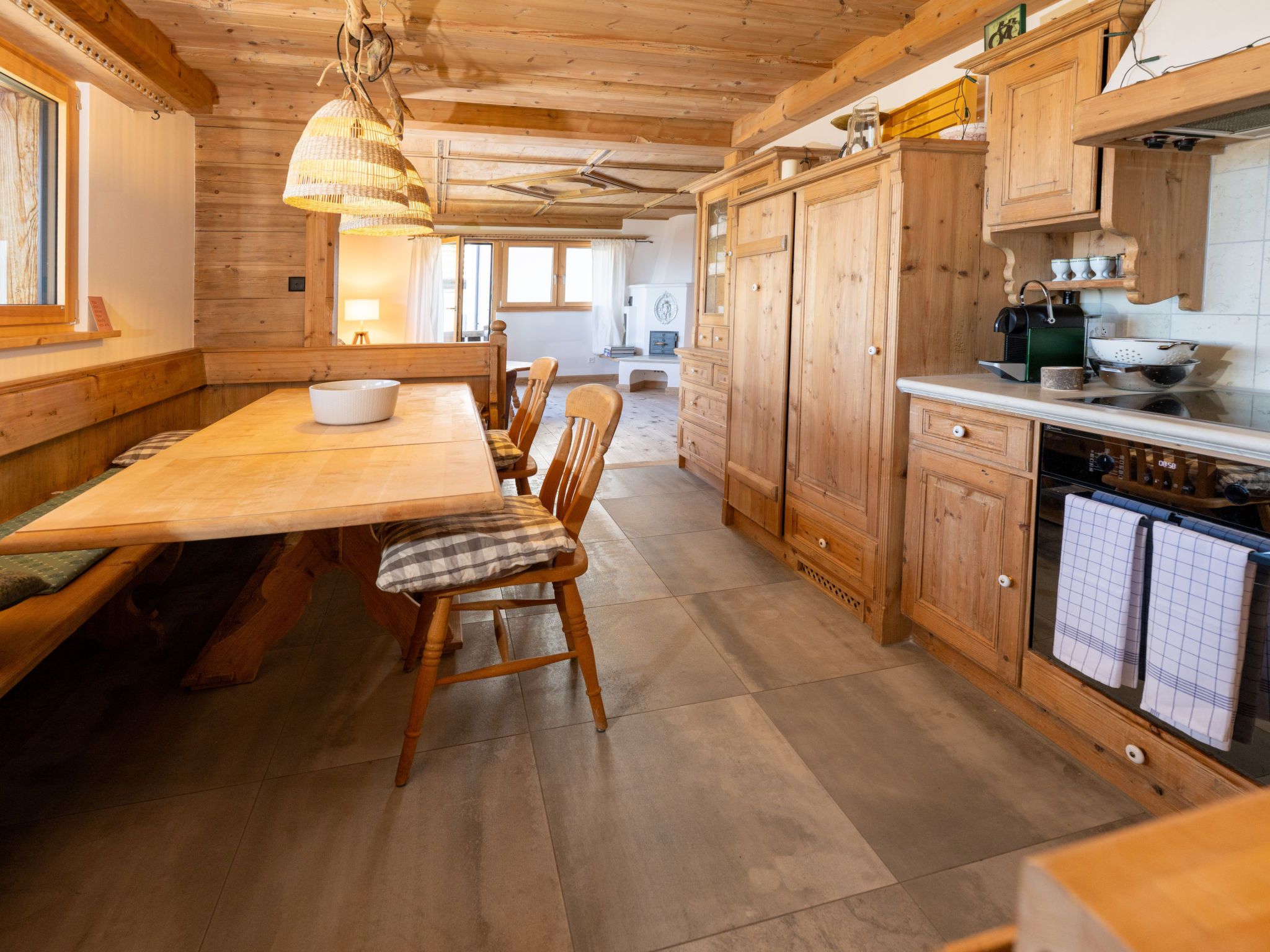 A wooden interior with a dining table, chairs, and a kitchen area.