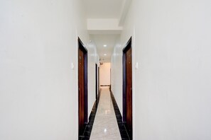 A corridor with doors on both sides, a tiled floor, and a ceiling with recessed lighting. - Townhouse Nagole Metro Station (Hyderabad)